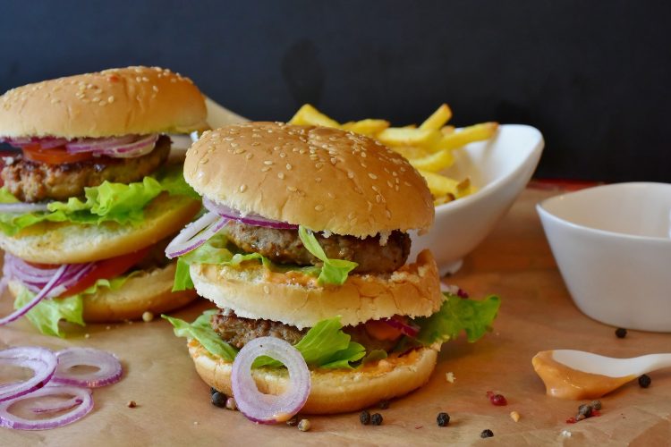 Dois sanduíches do tipo hamburguer. Cada um possui duas carnes, três pães, queijo e salada. 