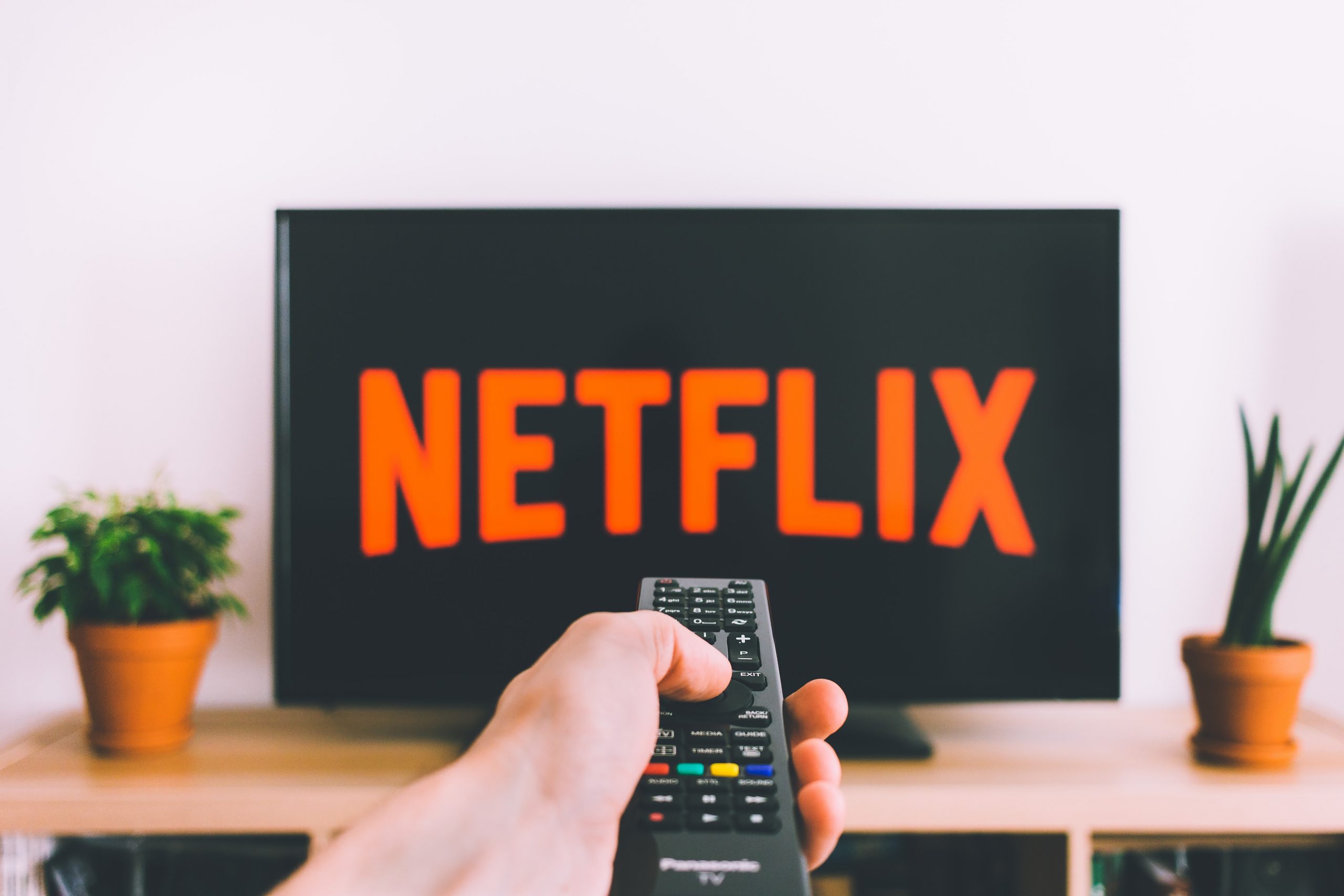 pessoa segurando controle remoto apontando para televisão. 5 filmes de liderança da Netflix