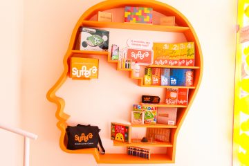 Estante em forma de cabeça humana com livros e outros produtos da marca Supera