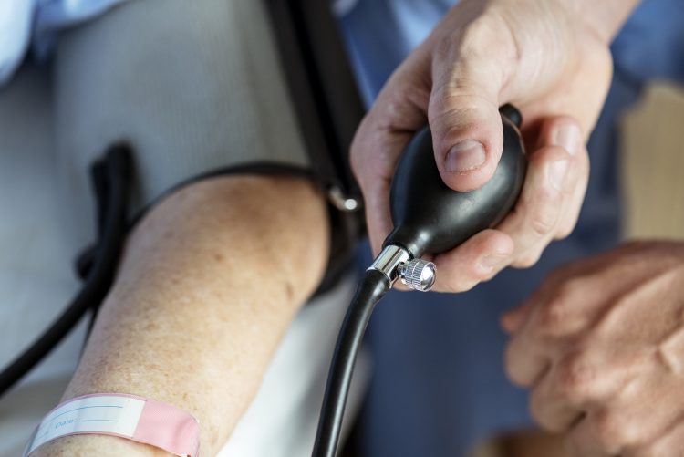 Profissional da saúde tirando pressão de paciente idoso; Médicos, enfermeiros e técnicos podem fazer sua pré-inscrição para a COAPH Saúde