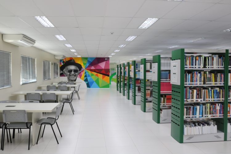 Cursos de curta duração: na imagem, a biblioteca da Unifametro, branca com estantes verdes e uma pintura colorida em uma das paredes.