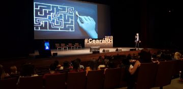 CearáRH: Na imagem, uma palestra do evento de 2019. O público está em um auditório escuro e, no palco, há um telão e uma escultura com o nome "#CearáRH" em branco.